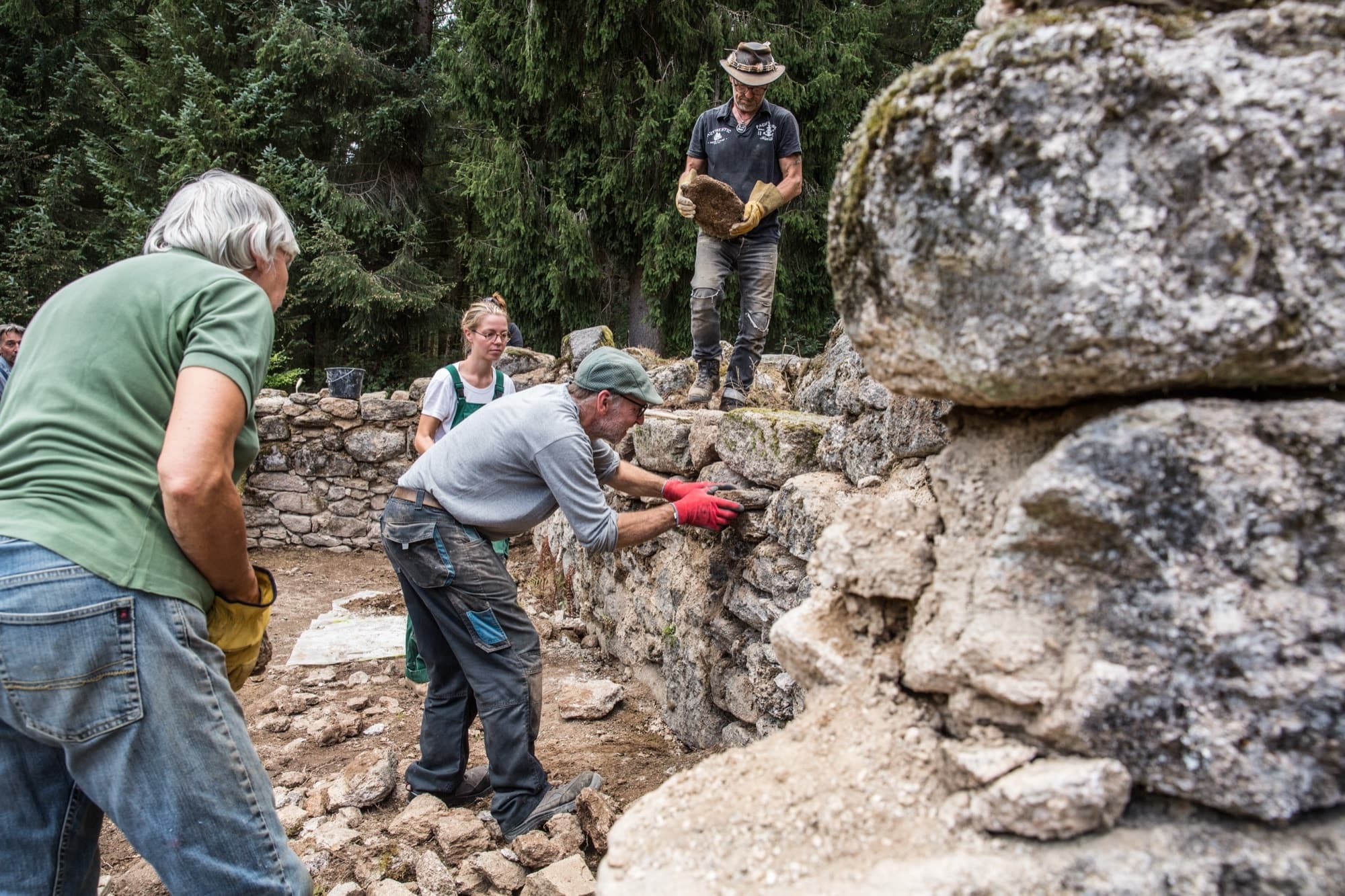 Trois restaurateurs posant des pierres sur un mur élevé en Corrèze
