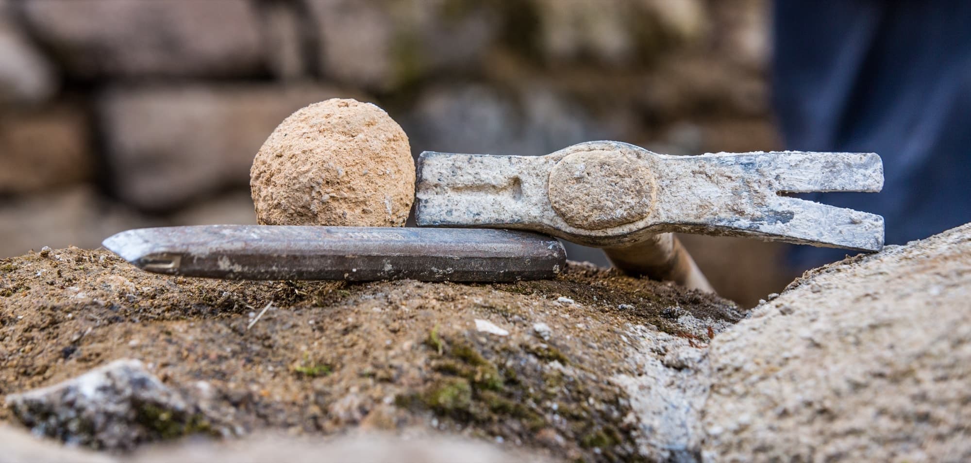 Marteau de tailleur de pierre et boule de mortier de chaux sur un muret