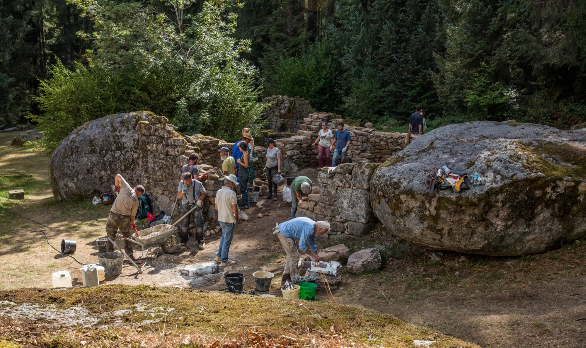 Vue large d'un chantier collectif entre deux rochers granitiques